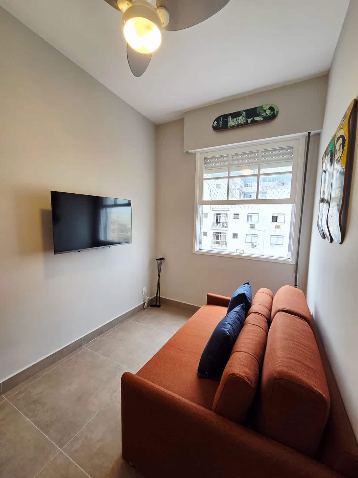 Sala com TV smart, ventilador de teto e sofá-cama